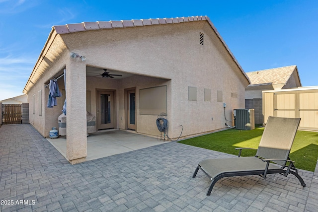 back of property with fence, central AC, ceiling fan, stucco siding, and a patio area