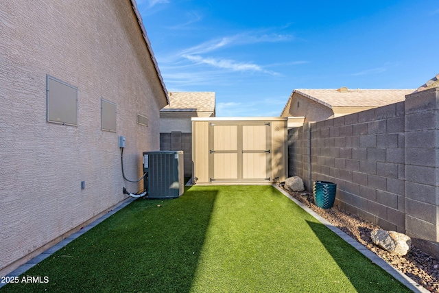 view of yard featuring central air condition unit, a storage unit, an outdoor structure, and a fenced backyard