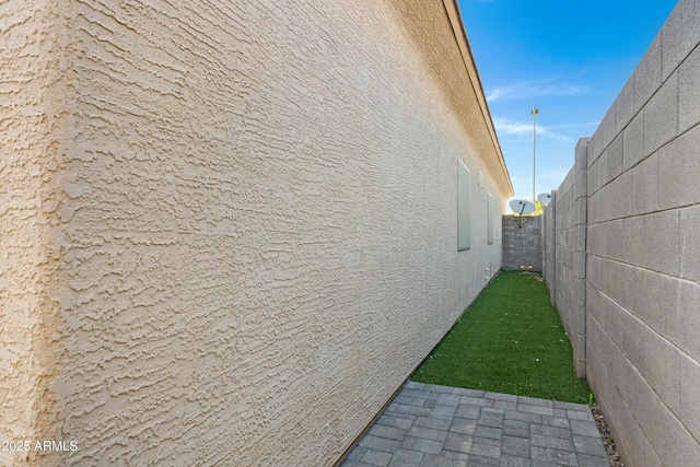 view of side of home with fence and stucco siding