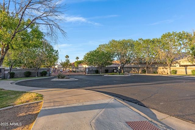 view of road with curbs, a gate, sidewalks, and a residential view