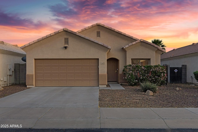 view of front facade with a tiled roof, a garage, driveway, and stucco siding