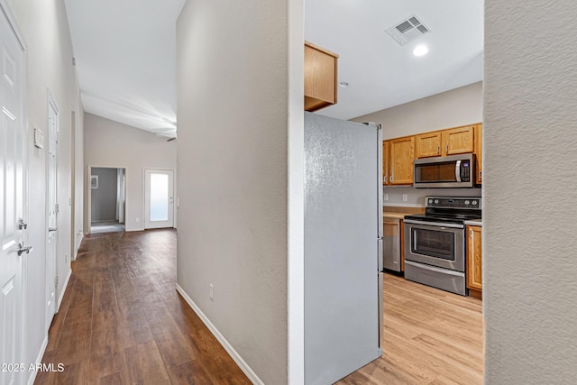 kitchen with stainless steel appliances, baseboards, visible vents, and light wood-style floors