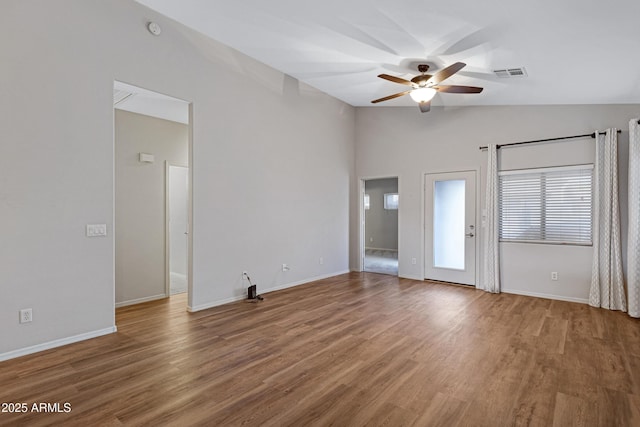 empty room featuring visible vents, wood finished floors, baseboards, ceiling fan, and vaulted ceiling