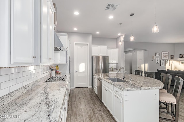 3884 S Wilson Dr, Chandler, AZ 85286 - kitchen with appliances with stainless steel finishes, a kitchen breakfast bar, decorative backsplash, an island with sink, and white cabinets