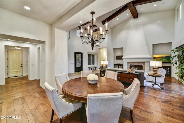 dining space with beamed ceiling, a fireplace, high vaulted ceiling, and wood-type flooring