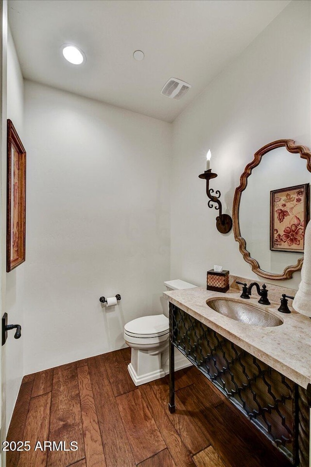 bathroom with hardwood / wood-style floors, vanity, visible vents, recessed lighting, and toilet