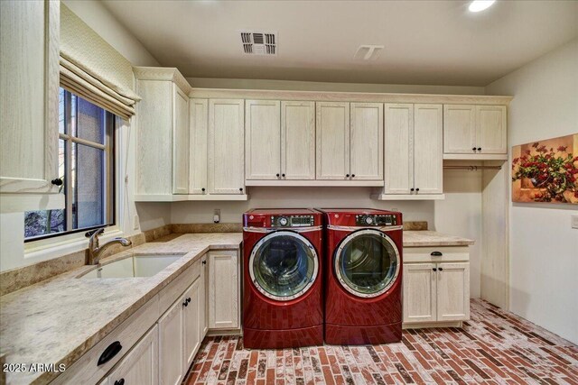 washroom with visible vents, cabinet space, brick floor, a sink, and independent washer and dryer