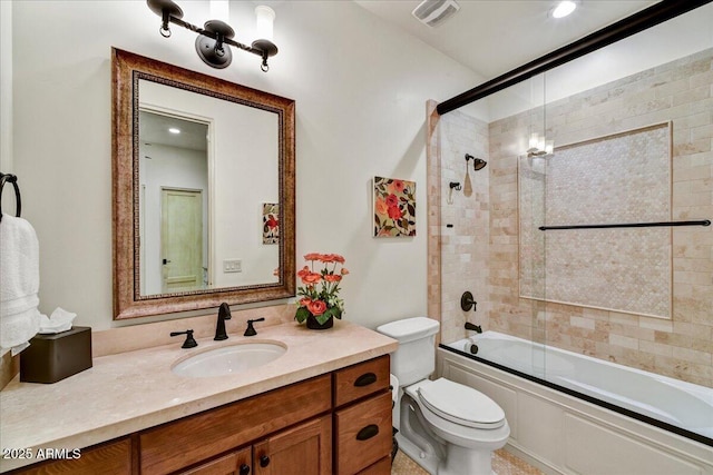 bathroom featuring visible vents, toilet, vanity, and shower / bath combination with glass door