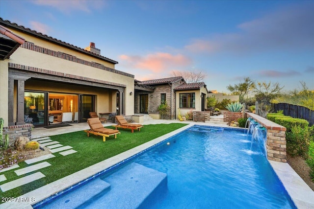 view of swimming pool featuring a fenced in pool, a patio, a lawn, and fence