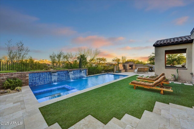 pool at dusk with fence, a fenced in pool, an in ground hot tub, exterior kitchen, and a lawn