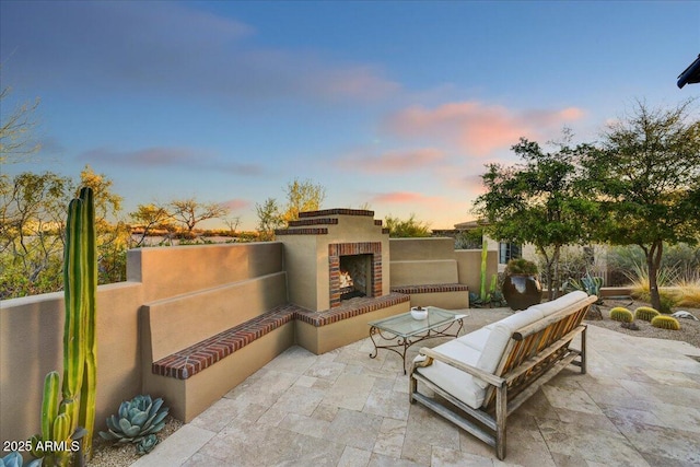 patio terrace at dusk with an outdoor living space with a fireplace