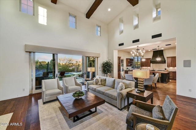 living area with wood-type flooring, a notable chandelier, beam ceiling, and a healthy amount of sunlight