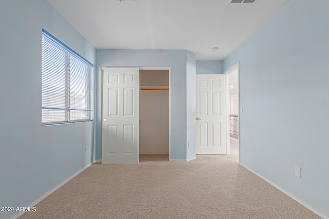 unfurnished bedroom featuring light colored carpet and a closet