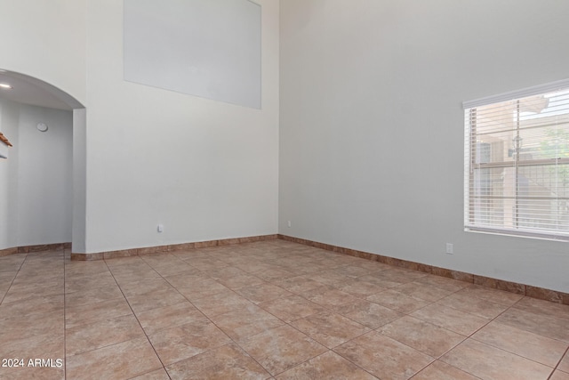 tiled empty room featuring a high ceiling