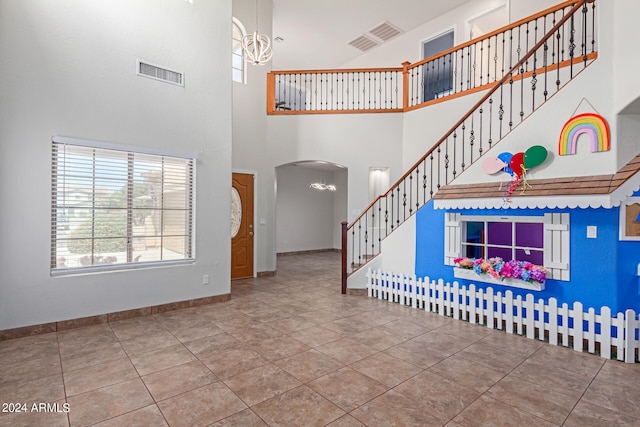 entryway with tile patterned floors and a towering ceiling