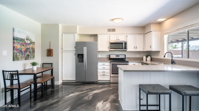2139 W Obispo Ave, Mesa, AZ 85202 - kitchen with stainless steel appliances, a sink, white cabinets, a peninsula, and light countertops