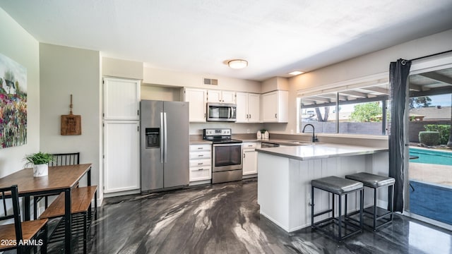 2139 W Obispo Ave, Mesa, AZ 85202 - kitchen with appliances with stainless steel finishes, a peninsula, white cabinets, a sink, and a kitchen bar