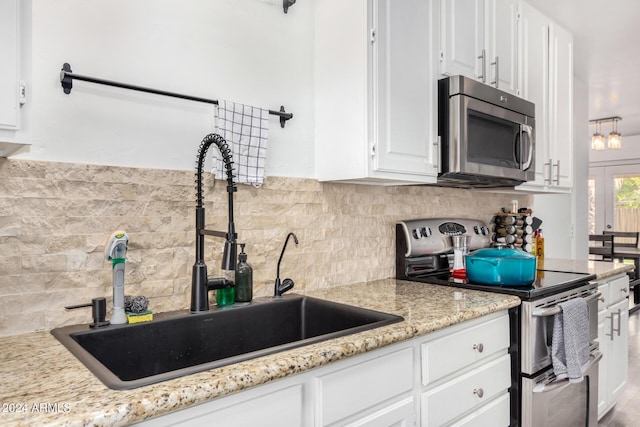 kitchen featuring light stone countertops, sink, stainless steel appliances, tasteful backsplash, and white cabinets