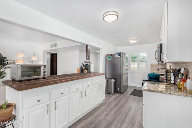 kitchen featuring wooden counters, backsplash, stainless steel appliances, white cabinets, and light hardwood / wood-style floors