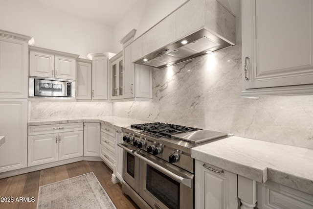 kitchen with stainless steel appliances, premium range hood, white cabinetry, and decorative backsplash