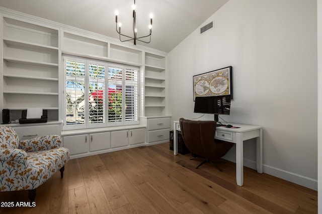 office space with built in shelves, hardwood / wood-style floors, and a notable chandelier