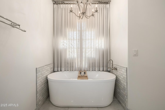 bathroom with a tub, tile walls, a notable chandelier, and tile patterned floors