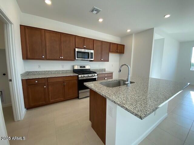 kitchen featuring light stone countertops, visible vents, recessed lighting, a sink, and stainless steel appliances