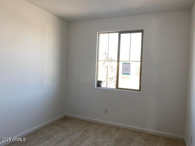 spare room featuring baseboards and light carpet