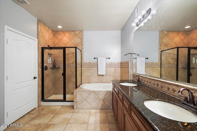 bathroom featuring tile patterned flooring, a shower stall, a garden tub, and a sink