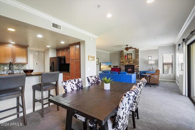 carpeted living room with a barn door, ceiling fan, ornamental molding, and a fireplace