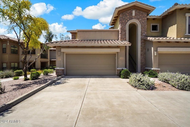 view of front of house with driveway, stucco siding, a garage, stone siding, and a tiled roof