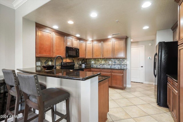 kitchen with tasteful backsplash, brown cabinets, a peninsula, and black appliances