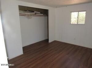 unfurnished bedroom featuring dark wood-type flooring and a closet