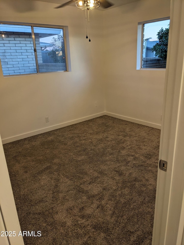 spare room featuring dark colored carpet and ceiling fan