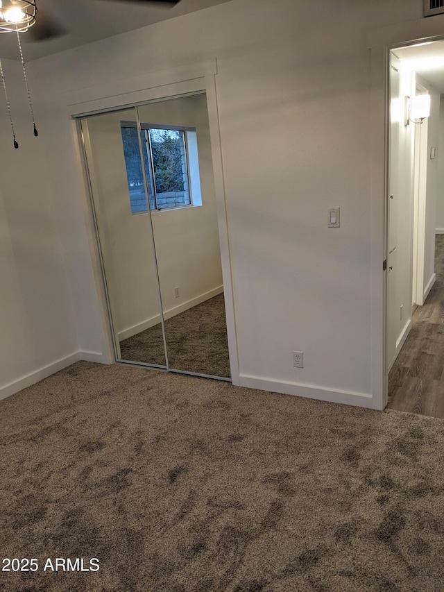 unfurnished bedroom with dark colored carpet and a closet