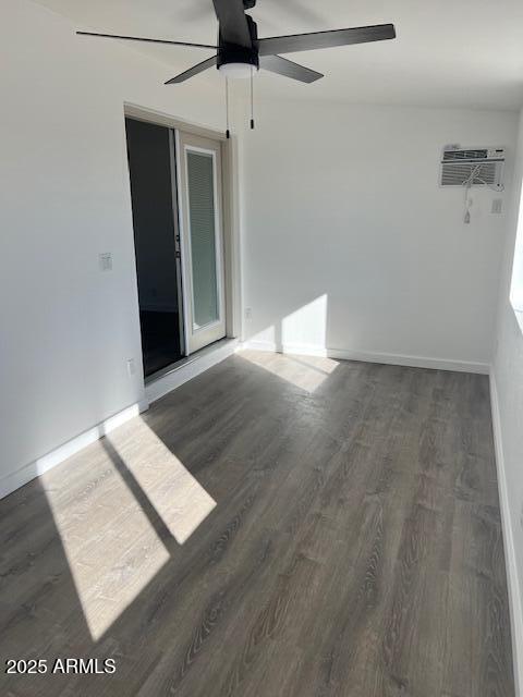 unfurnished room with dark wood-type flooring, an AC wall unit, and ceiling fan