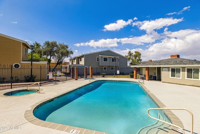 community pool featuring fence, a hot tub, and a patio area