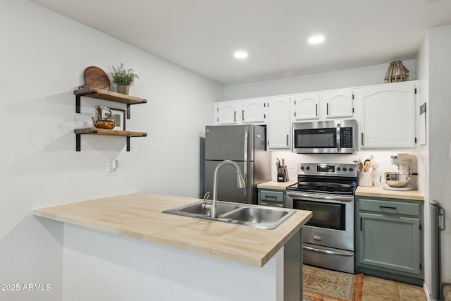 kitchen with stainless steel appliances, a sink, a peninsula, white cabinets, and light countertops