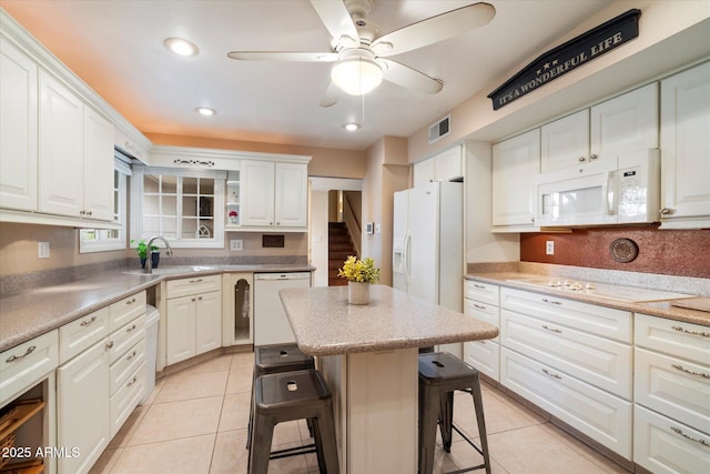 kitchen featuring white appliances, a sink, a breakfast bar area, a ceiling fan, and white cabinets