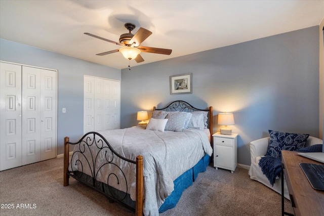 bedroom with two closets, carpet floors, a ceiling fan, and baseboards