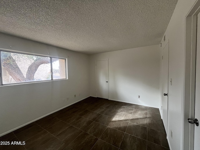 tiled spare room featuring a textured ceiling