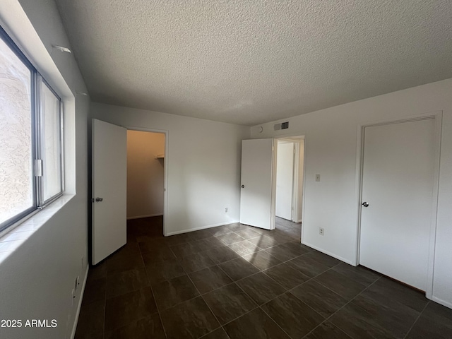 unfurnished bedroom with a walk in closet, a textured ceiling, and a closet