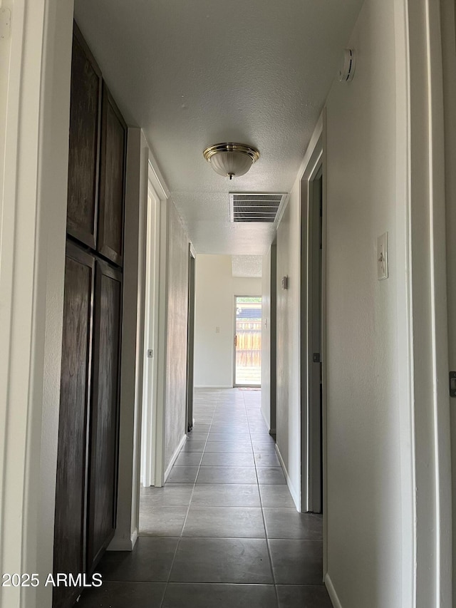 corridor with light tile patterned flooring and a textured ceiling