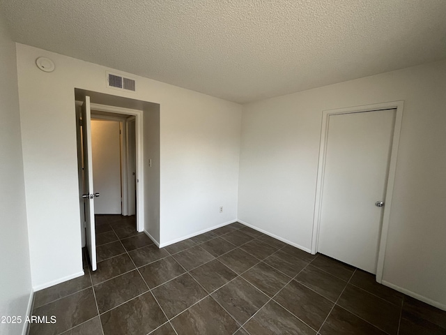 tiled spare room featuring a textured ceiling