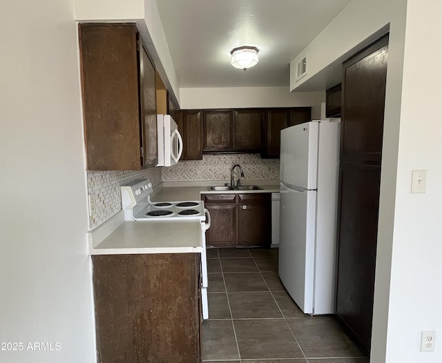 kitchen with sink, white appliances, dark tile patterned floors, dark brown cabinets, and decorative backsplash