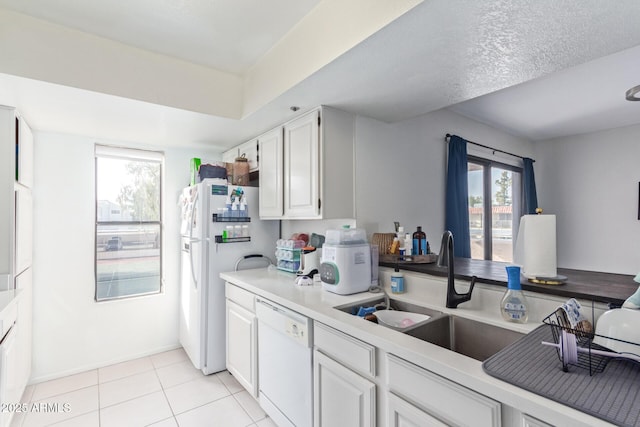 kitchen featuring white cabinetry, white appliances, light tile patterned flooring, and sink