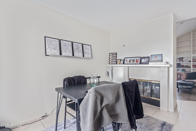 dining area featuring light tile patterned floors, built in shelves, and a tile fireplace