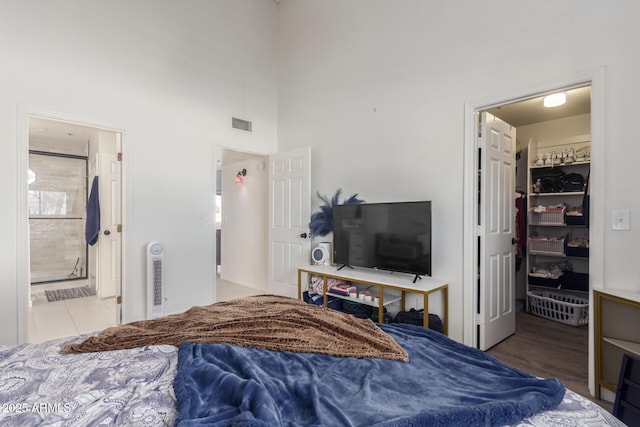 bedroom featuring a closet, a spacious closet, connected bathroom, and a towering ceiling