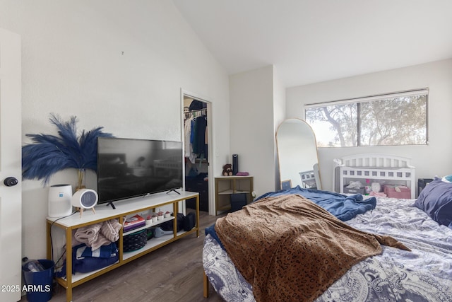 bedroom with lofted ceiling, a walk in closet, dark hardwood / wood-style flooring, and a closet