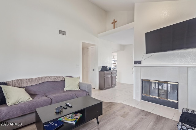 living room with light tile patterned floors, a fireplace, and high vaulted ceiling